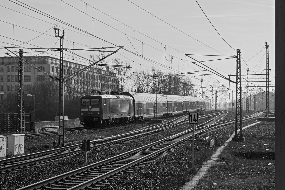 Aus dem hrtesten Gegenlicht heraus erreicht 112 190 den Bahnhof Berlin-Sdkreuz.