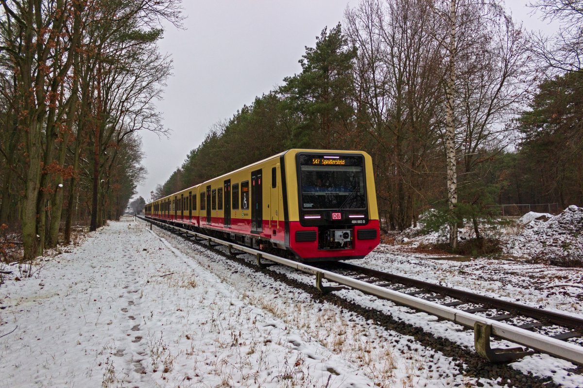 Die S-Bahn-Linie S47 fhrt zwischen Schneweide und Spindlersfeld abwechselnd durch den Wald und durch die Hinterhfe von Industriebetrieben. Obwohl das Gebiet also nicht allzu dicht besiedelt ist, gab es bis in die 90er-Jahre neben der S-Bahn auch eine Buslinie, deren Endstelle Oberspree rechts von der Position lag, die die Garnitur 484 003 am 04.01.2020 gerade passiert. Die Wendeschleife war noch bis vor kurzem befahrbar, obwohl seit langer Zeit nicht mehr genutzt.